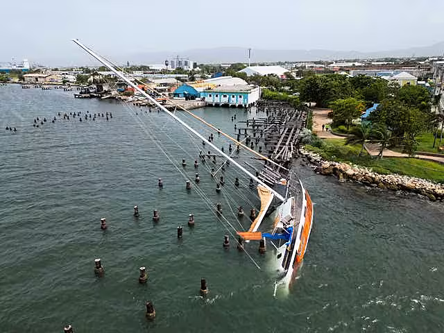 A boat damaged by Hurricane Beryl lays on its side at a dock in Kingston, Jamaica