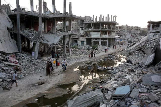 Palestinians walk next to a dark streak of sewage in Khan Younis