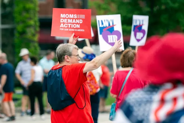 Paradegoers with Moms Demand Action march during the Independence Day Parade along Central Avenue in Highland Park 