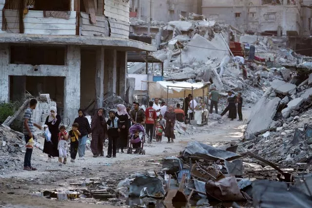 Palestinians displaced by the Israeli air and ground offensive on the Gaza Strip walk next to a dark streak of sewage flowing into the streets of the southern town of Khan Younis 