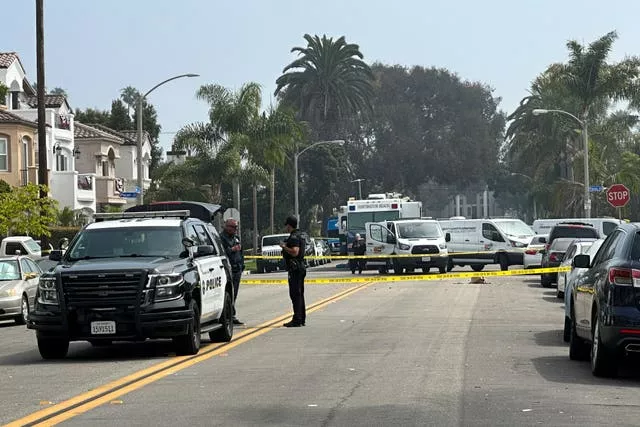 Police officers stand guard at the crime scene where police say two people were killed and three others injured in Huntington Beach, California