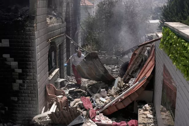 A Palestinian first responder navigates the rubble of a home 