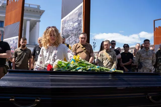 A woman looks at flowers on a coffin