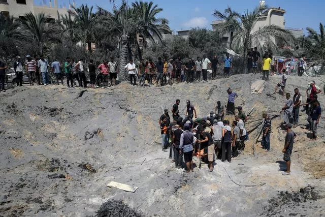 A group of people dig in a bomb crater