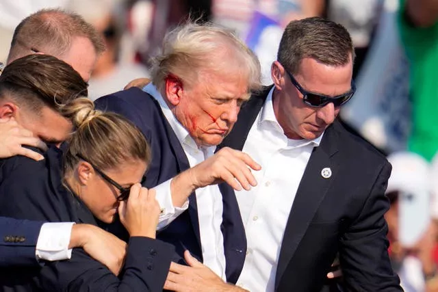 Former US president Donald Trump being helped off the stage after the shooting