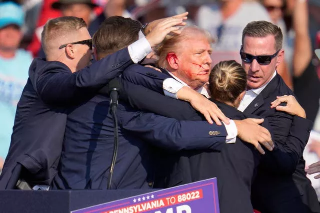 A man with blood on his face surrounded by men in suits