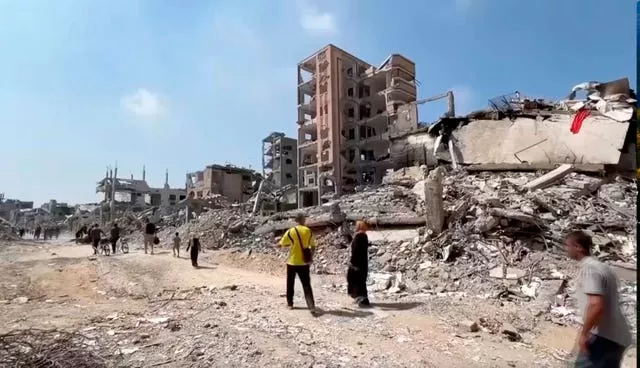 People walk through a devastated neighbourhood