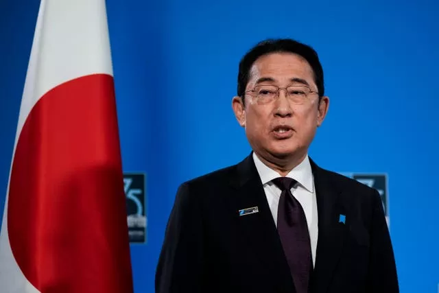 Japan’s Prime Minister Fumio Kishida speaks in front of a Japan flag