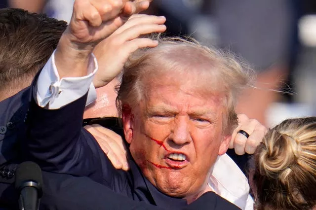 Donald Trump raises his fist in the aftermath of the shooting