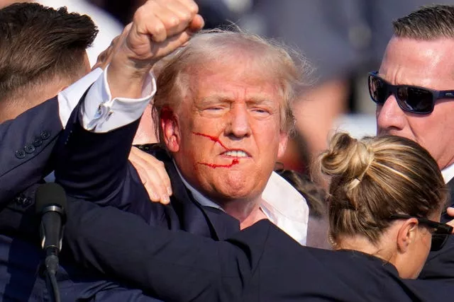 Donald Trump, with blood on his face, raises a fist 