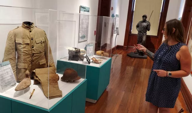 Woman in blue dress points at artefacts in glass cases at Key West Museum of Art & History