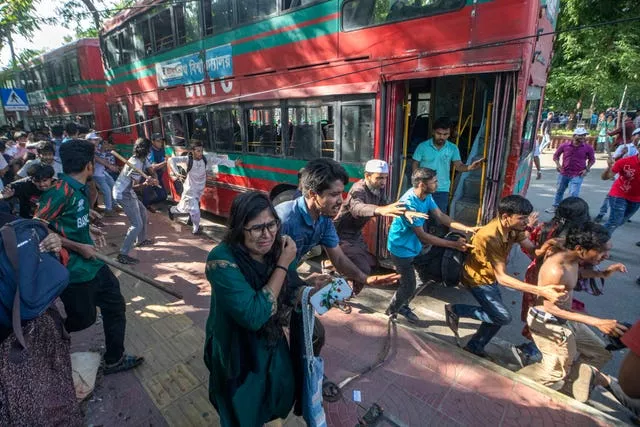 People running past buses as they flee violent clashes in Bangladesh