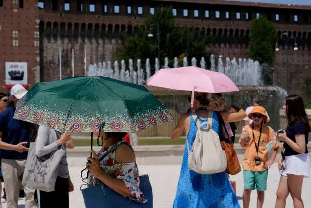 گردشگران در مقابل قلعه Sforzesco در میلان ایتالیا از خود در برابر نور خورشید محافظت می کنند