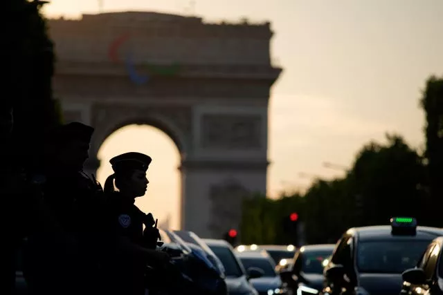 French police officer silhouetted with the arc de triomphe in the background