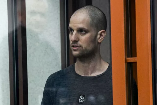 Evan Gershkovich stands listening to the verdict in a glass cage