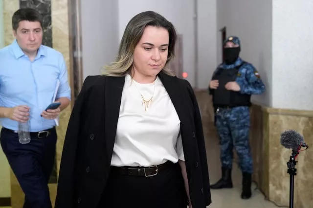 Lawyer Maria Korchagina walking theough court building with guard and another man in background