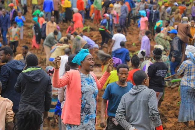 a woman cries as hundreds of people gather at the site of a mudslide