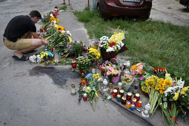 People lay flowers and light candles at a makeshift memorial in tribute to Iryna Farion in Lviv