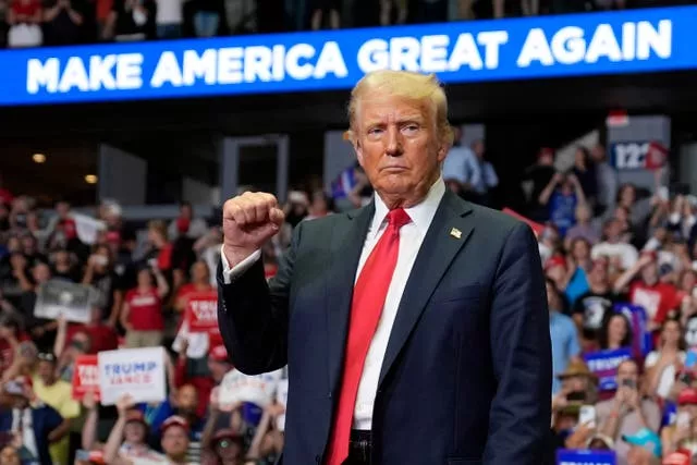 Donald Trump raises a clenched fist in front of supporters