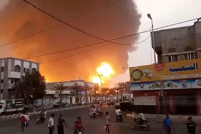 Fire in the distance, with people walking in the foreground