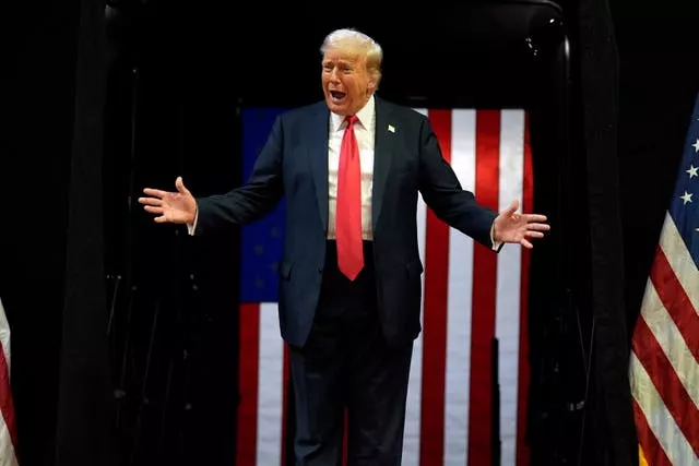 Donald Trump at a campaign rally, with an American flag in the background