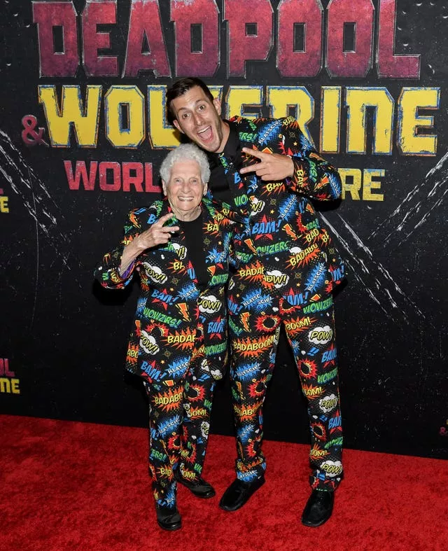 Ross Smith and his grandmother Pauline Kana pose with peace signs in matching multi-coloured suits