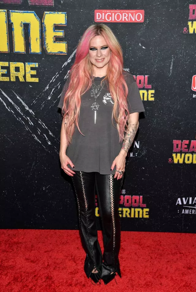 Avril Lavigne poses in leather black trousers and grey baggy t-shirt on red carpet