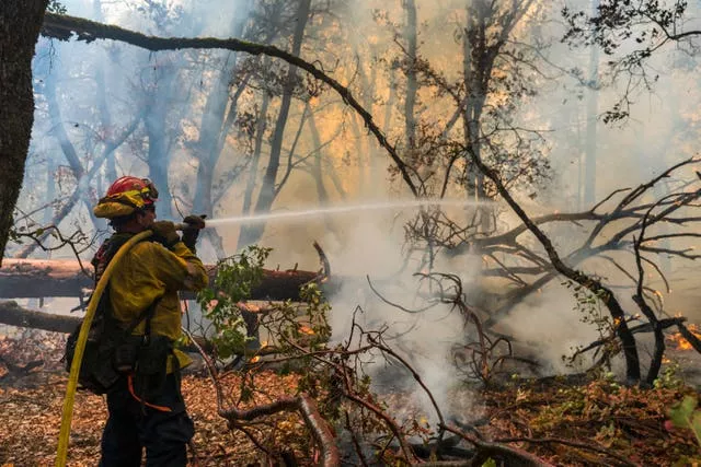 A firefighter sprays water on a fire burning in California