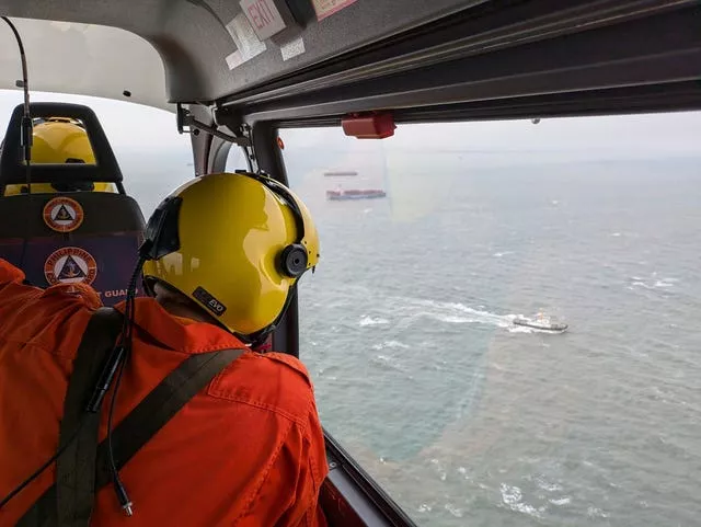 A coastguard officer monitors the sea from an aircraft window