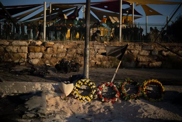 Wreath of flowers are placed on the site of the rocket strike on a football pitch