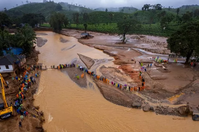 Rescuers on their second day of mission following Tuesday’s landslides cross a river at Chooralmala, Wayanad district, Kerala state