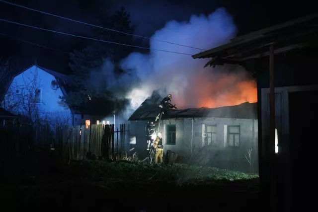 Rescue workers extinguish the fire of a house which was destroyed after a Russian drone strike on a residential neighbourhood in Kharkiv, Ukraine