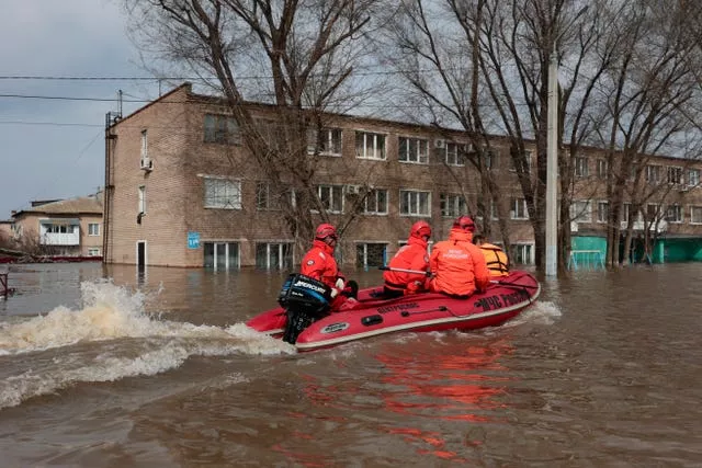 Emergency teams ride a boat along a flooded street in Orenburg, Russia 