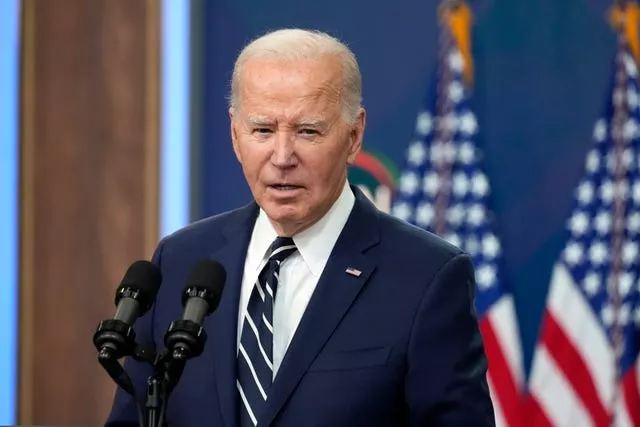 President Joe Biden speaking with American flags in the background