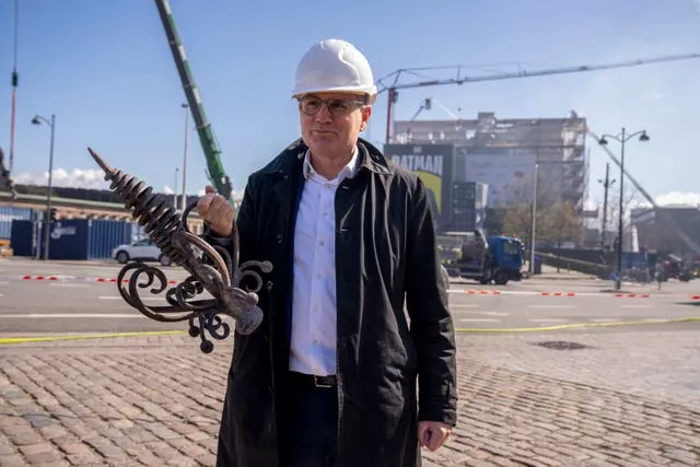 Danish Business CEO Brian Mikkelsen holds the top of the burnt dragon spire in front of Boersen 