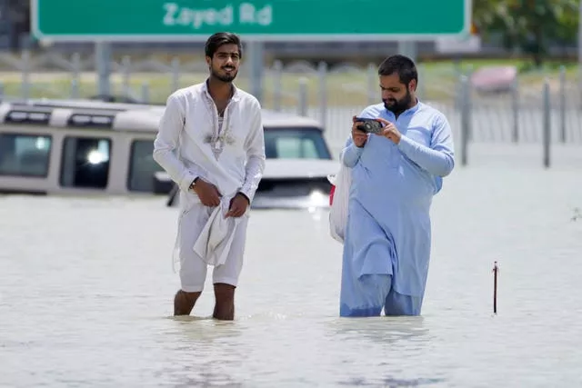 Dois homens caminham pelas enchentes em Dubai 