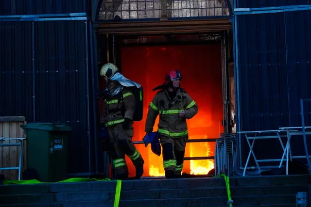 Firefighters walk out of the main entrance as the Old Stock Exchange burns in Copenhagen, Denmark 