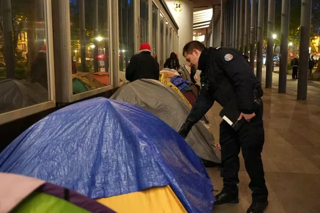 A police officers checks a migrant’s tent 
