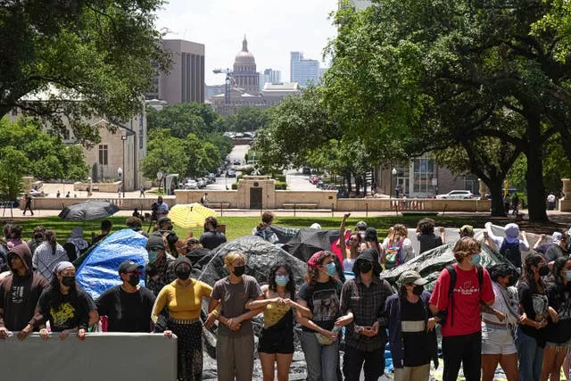 Manifestantes dão os braços em um acampamento na Universidade do Texas em Austin
