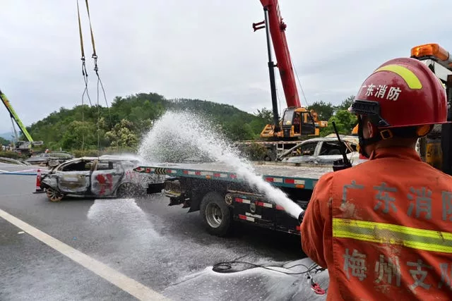 Um bombeiro borrifa água nos restos de um carro após o desabamento da estrada