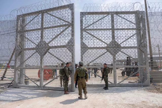 Israeli soldiers gather near a gate to walk through an inspection area for trucks carrying humanitarian aid supplies bound for the Gaza Strip