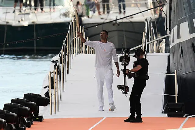 French Olympic swimmer Florent Manaudou holds the Olympic torch after leaving the Belem, the three-masted sailing ship in the Old Port of Marseille, southern France