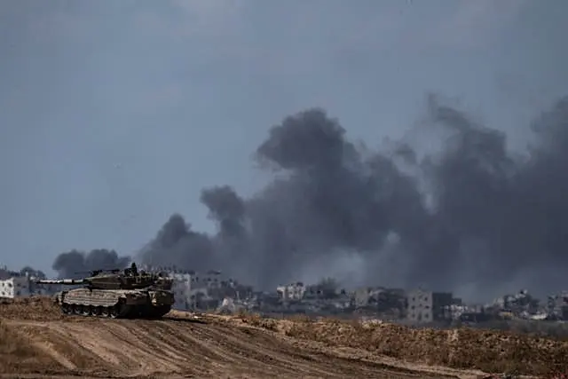 Backdropped by smoke rising to the sky after an explosion in the Gaza Strip, an Israeli tank stands near the Israel-Gaza border as seen from southern Israel 