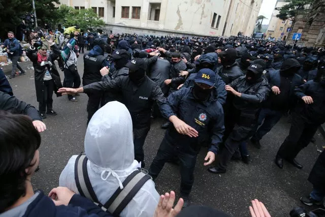 A polícia bloqueia manifestantes perto do edifício do parlamento durante um protesto da oposição contra a “lei russa” no centro de Tbilisi, Geórgia 