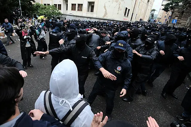 A polícia bloqueia manifestantes perto do edifício do parlamento durante um protesto da oposição contra a “lei russa” no centro de Tbilisi, Geórgia 