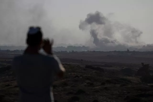 A man watches smoke rising to the sky after an explosion in the Gaza Strip