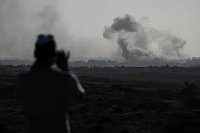 A man watches smoke rising to the sky after an explosion in the Gaza Strip