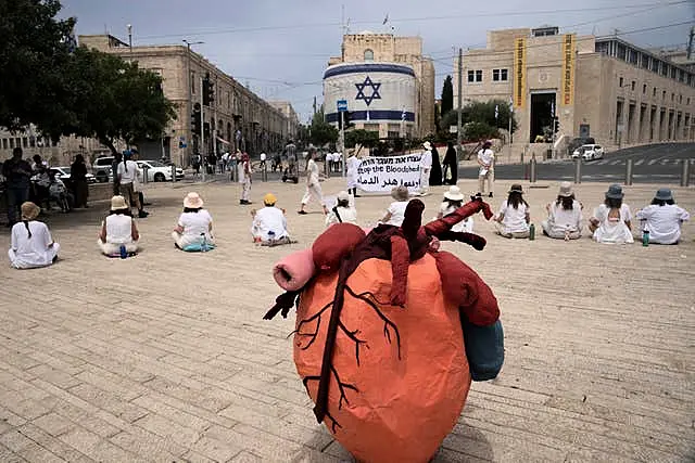 Women activists hold a silent protest with placards in Arabic, Hebrew and English calling for a ceasefire in the Gaza Strip and safety, freedom and equality for Israelis and Palestinians, outside of the walls of the Old City of Jerusalem 