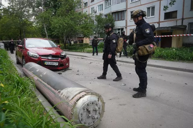 Police officers inspect part of a Russian missile that fell close to an apartment building in Kharkiv, Ukraine