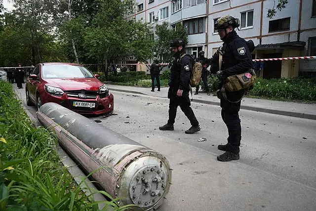 Police officers inspect part of a Russian missile that fell close to an apartment building in Kharkiv, Ukraine